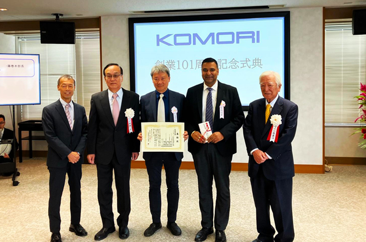 Komori India receiving the President Special Award for Best Sales Team during Komori Corporation 101st anniversary celebrations, with senior leadership on stage applauding the India team’s achievement