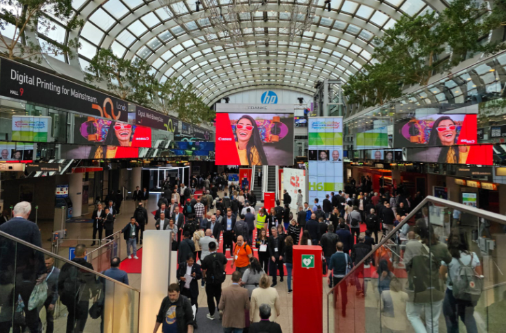 Drupa 2024 international trade fair exhibition hall with global exhibitors and visitors from printing and packaging industries exploring machinery, technology, and innovation showcases