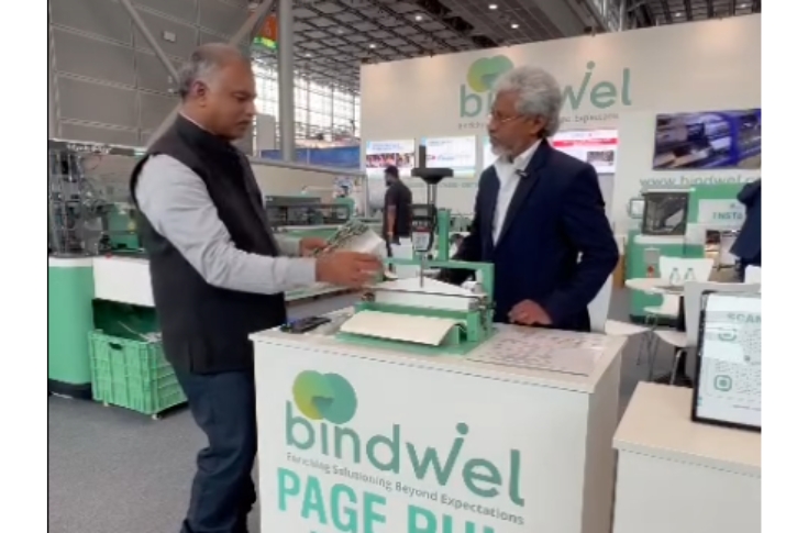 Suresh Nair from Bindwel-Stelda Group demonstrating a portable page pull tester at Drupa 2024, highlighting bookbinding strength testing and print quality assurance technology