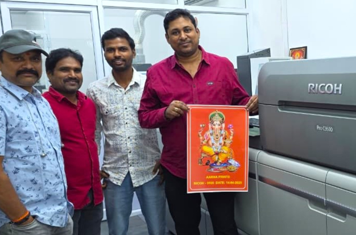 Ricoh Pro C9500 digital colour production press operating in a print lab, producing high-quality photo albums with high-speed output and handling a wide range of paper weights and substrates