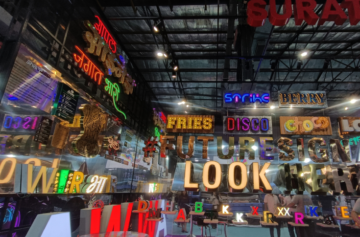 Snapshots from Day One of the 50th Media Expo at Bombay Exhibition Centre, Goregaon, showing exhibition halls with printing and signage technology displays and visitors exploring the event