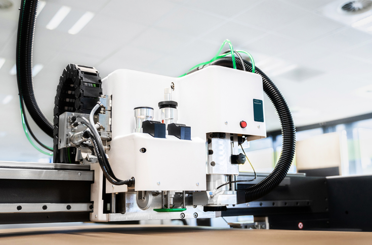 Rafiq Shaikh from Kongsberg Precision Cutting Systems demonstrating the Kongsberg X24 cutting table, showcasing automated tool changes, packaging prototypes, and 3D display cutting applications for high-speed production efficiency