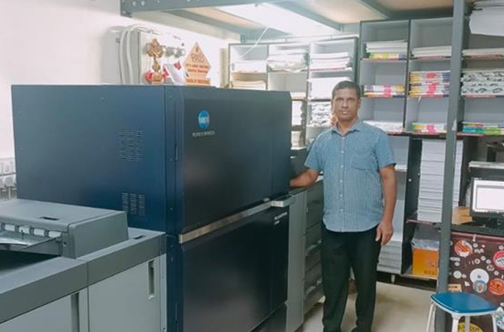 Commercial print shop featuring Konica Minolta digital presses in operation, including high-speed colour and monochrome printing systems for production-scale output