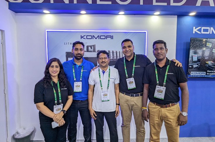 Komori India exhibition booth at Bharat Print Expo showcasing Lithrone printing presses under Connected Automation theme with commercial and packaging industry visitors interacting with advanced offset printing technology
