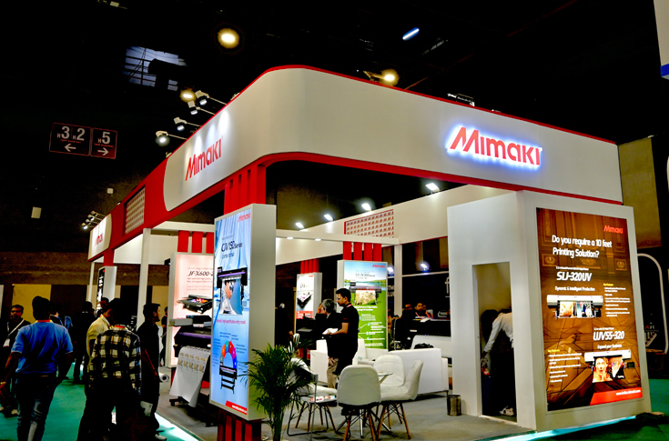 Kenichiro Seki of Mimaki India showcasing advanced UV and eco-solvent printing solutions, including the UCJV330 Series, UJV100-160Plus, CJV150-160 printer, CG cutting plotters, and UJF-6042MkII e flatbed printer at the Mimaki India booth