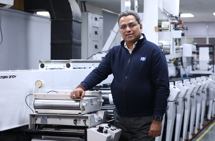 Flexo Image Graphics (FIG) stand at Labelexpo India 2024 featuring Rhyguan die-cutting machine, Luster inspection system, and Mark Andy printed label samples display