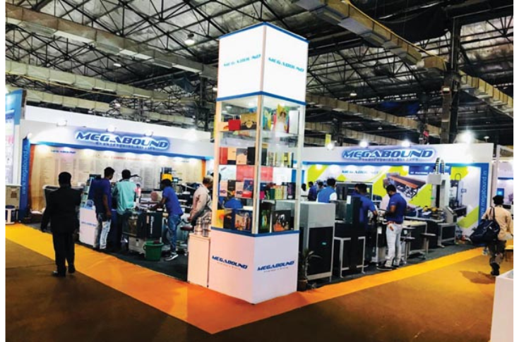 Megabound displaying hard-case binding machines, case-makers, spine cutters, and rigid box-making equipment at PrintPack 2025 trade fair