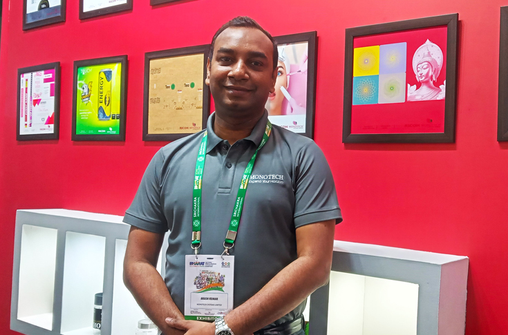 Monotech Systems booth at Bharat Print Expo 2025 displaying Ricoh Pro C7500 digital press, Pixel Glow Lumina embellishment system, Tracesci Razor 6 inkjet track and trace solution, Jetsci inkjet samples, Mimaki UV printer, Canon image PROGRAF plotter, and post-press finishing equipment